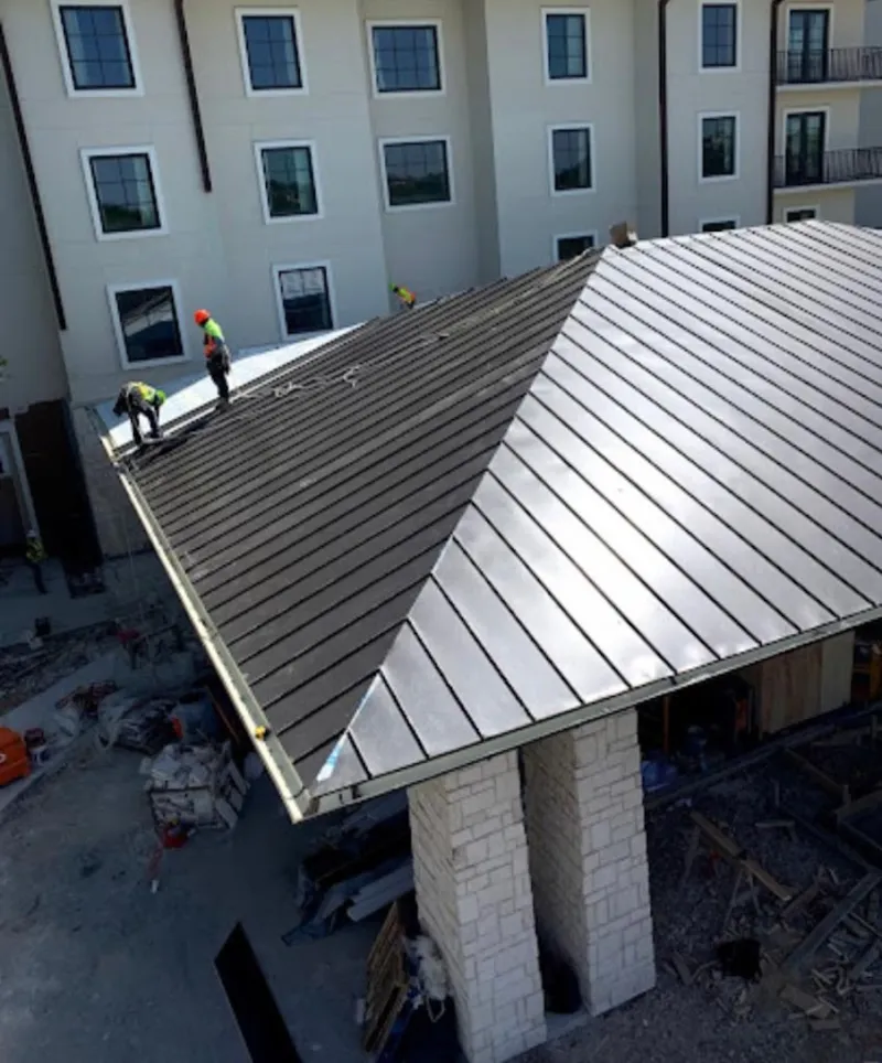 Crew installing standing seam metal roof panels on a commercial project in Ipswich